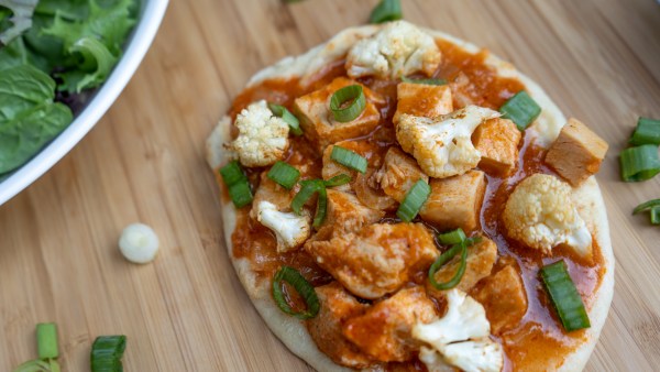 Butter Chicken Pizza on Naan with cauliflower and green onion on top