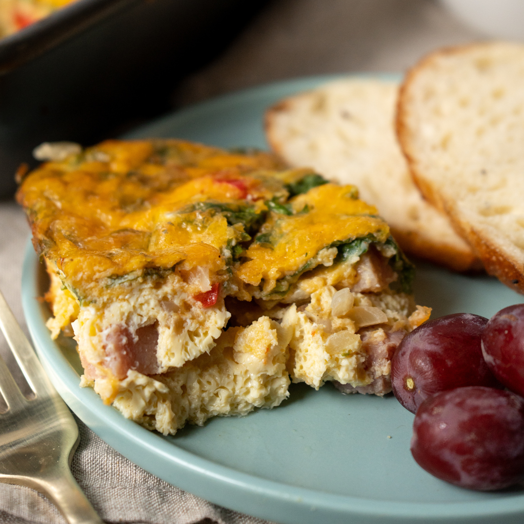 ham and cheese frittata with veggies on a plate with grapes and sourdough toast