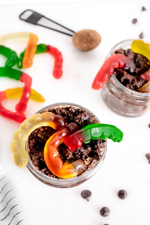 overhead shot of oreo overnight oats with gummy worms coming out of them on a white background