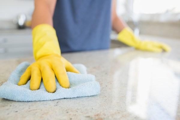 Woman cleaning the counter  in the kitchen wearing yellow gloves