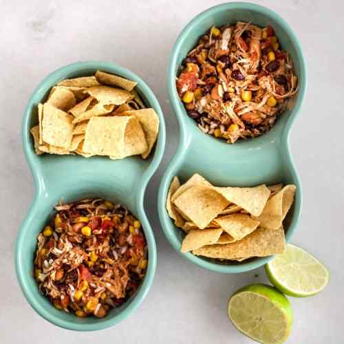 two dual sided blue bowls with taco chicken and rice slow cooker in one side and tortilla chips in the other