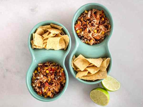 blue bowls with slow cooker taco chicken and rice in one side and chips in the other