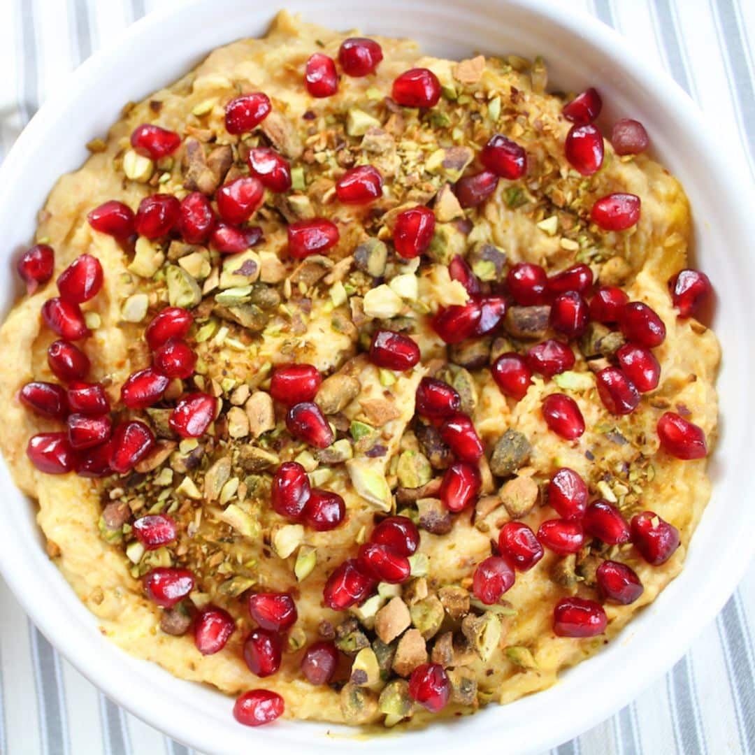 white bowl with butternut squash and goat cheese dip with pomegranate seeds and pistachios on top