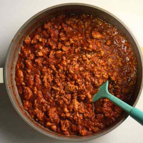 Pan filled with ground chicken sloppy joes and a teal spatula
