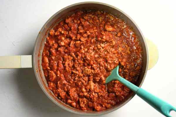 Pan filled with ground chicken sloppy joes and a teal spatula