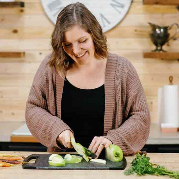 woman in kitchen slicing green apple