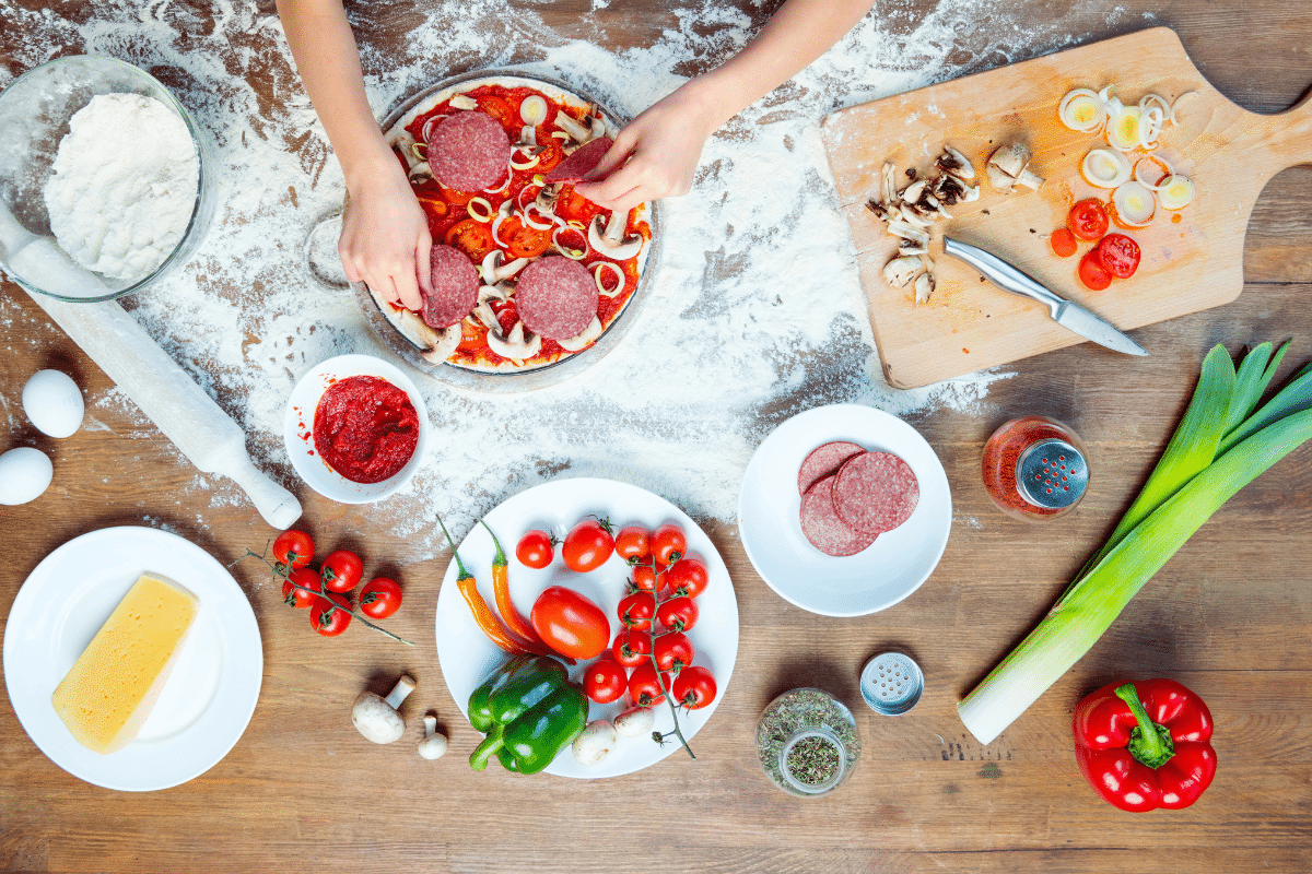 top view of children preparing pizza dough and pizza with various toppings