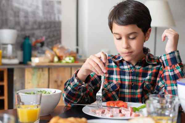 boy eating from plate with a fork at the table